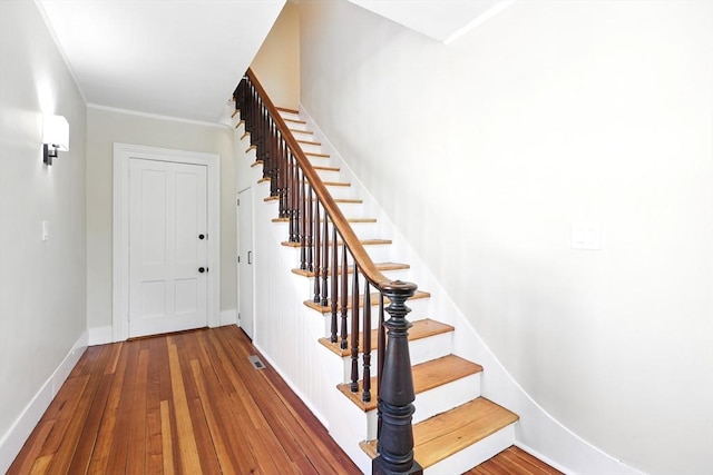 staircase with visible vents, baseboards, and wood finished floors