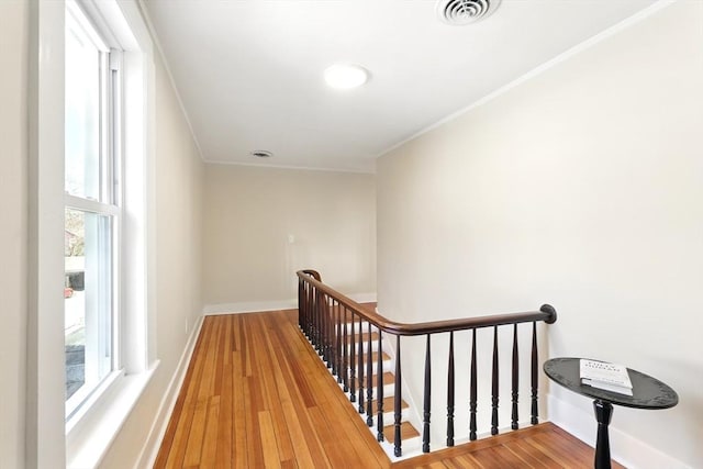 stairs with a wealth of natural light, visible vents, baseboards, and wood finished floors