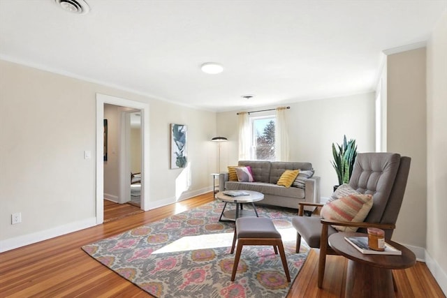 living room with visible vents, baseboards, and wood finished floors