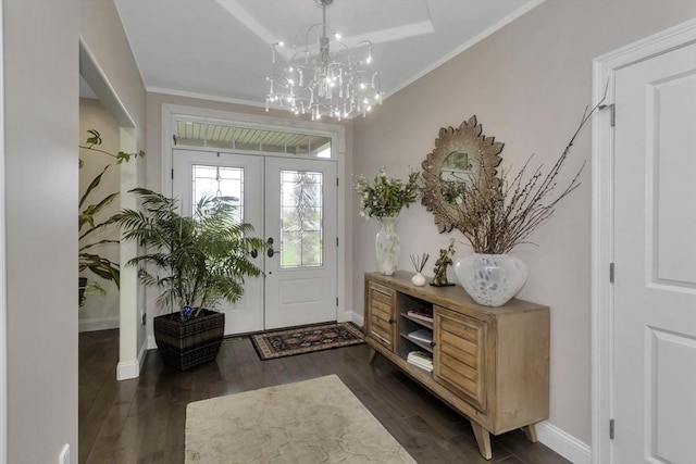 foyer with wood finished floors, a chandelier, baseboards, and ornamental molding