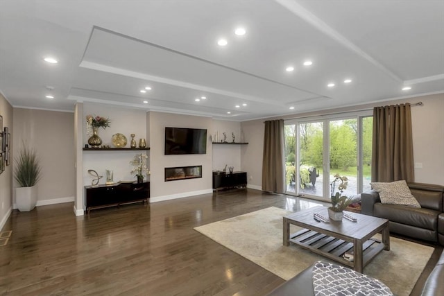 living room featuring wood finished floors, baseboards, a glass covered fireplace, recessed lighting, and crown molding