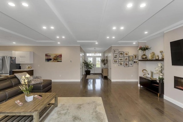 living room featuring baseboards, dark wood-type flooring, recessed lighting, a glass covered fireplace, and a chandelier