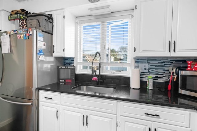 kitchen featuring stainless steel appliances, backsplash, a sink, and white cabinets