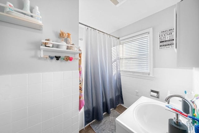 full bathroom featuring wainscoting, a sink, tile walls, and a shower with curtain