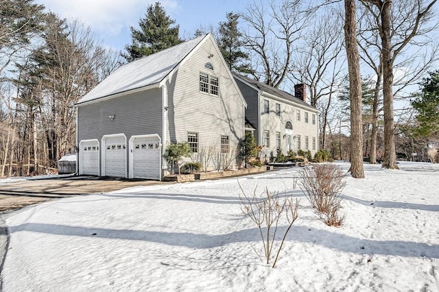 snow covered property with a garage