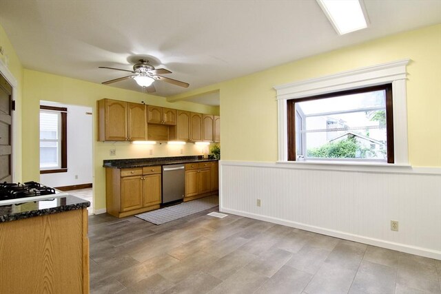 82 Worcester St, West Springfield, MA 01089 - kitchen with stainless steel dishwasher, stovetop, ceiling fan, wainscoting, and dark stone counters