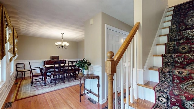 659 Sherman Farm Rd, Burrillville, RI 02830 - staircase with a chandelier, wood finished floors, a wainscoted wall, and a decorative wall