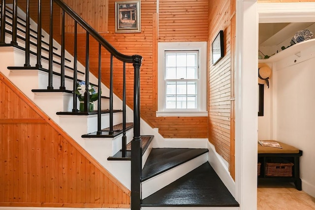 staircase with tile patterned flooring and wooden walls