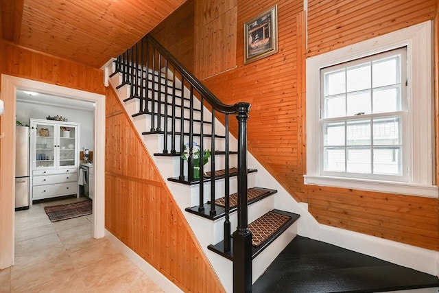 stairs with tile patterned flooring, wooden ceiling, and wood walls