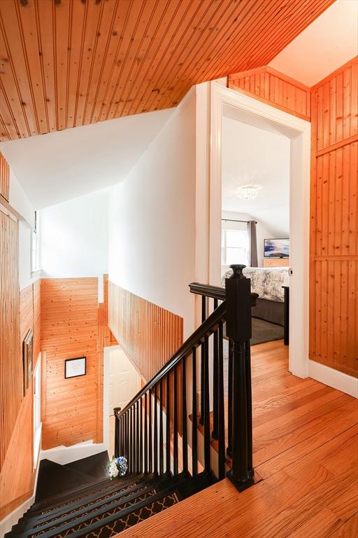 stairway with a healthy amount of sunlight, wooden ceiling, and wooden walls