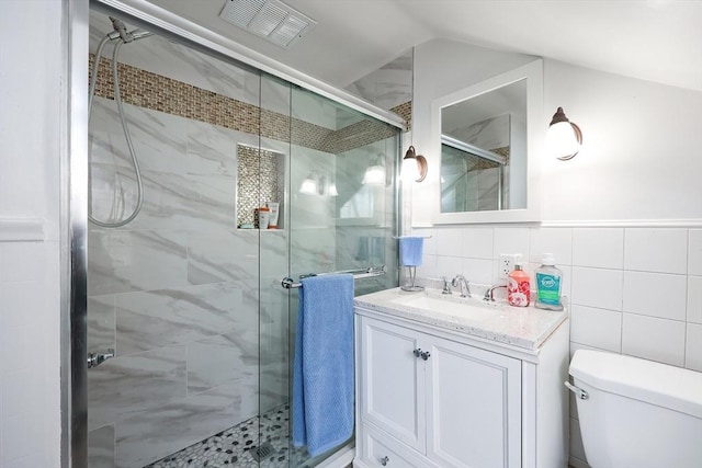 bathroom with toilet, an enclosed shower, tile walls, and vanity