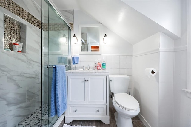 bathroom with toilet, a shower with door, vanity, and tile walls