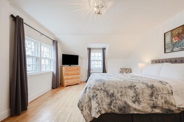 bedroom featuring lofted ceiling, an inviting chandelier, and hardwood / wood-style flooring