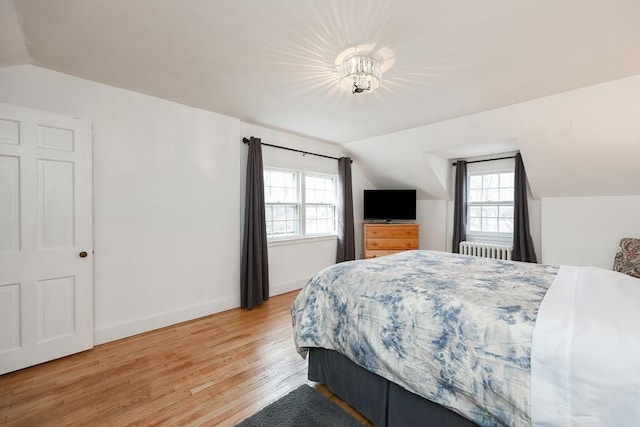 bedroom with lofted ceiling, light hardwood / wood-style floors, and radiator heating unit