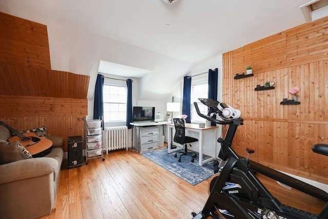 office space featuring radiator, wood walls, light wood-type flooring, and vaulted ceiling