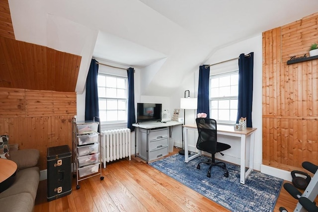 office area with wooden walls, light hardwood / wood-style flooring, radiator heating unit, and plenty of natural light