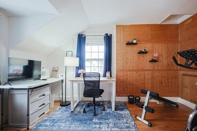 office space featuring lofted ceiling, hardwood / wood-style flooring, and wood walls