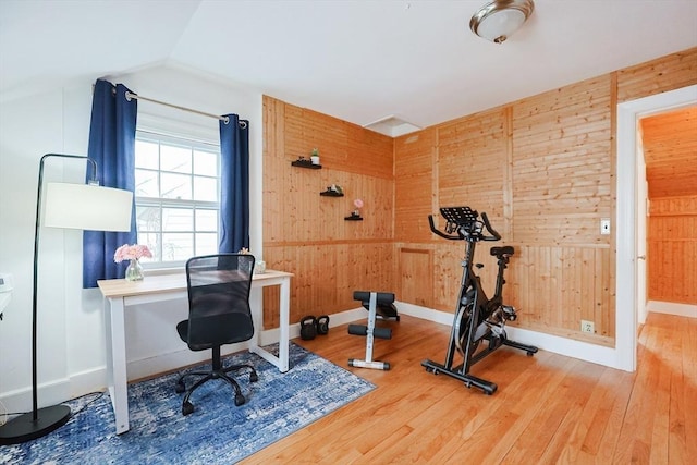 workout area featuring vaulted ceiling, wooden walls, and hardwood / wood-style floors