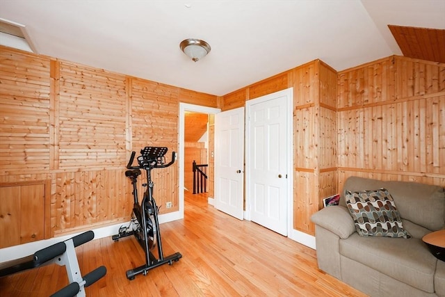 workout room with wooden walls, vaulted ceiling, and hardwood / wood-style flooring