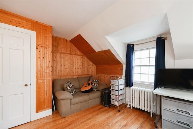 interior space featuring wood walls, lofted ceiling, and radiator