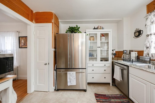 kitchen featuring stainless steel appliances, white cabinetry, and light stone counters