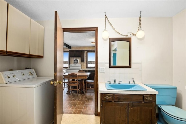 interior space featuring vanity, washer / clothes dryer, decorative backsplash, and toilet