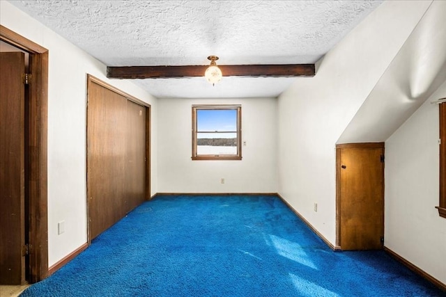 additional living space featuring beamed ceiling, dark carpet, and a textured ceiling