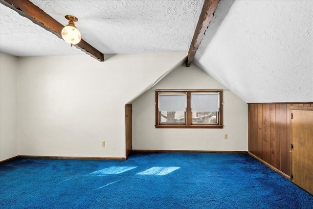 additional living space with dark colored carpet, vaulted ceiling with beams, and a textured ceiling