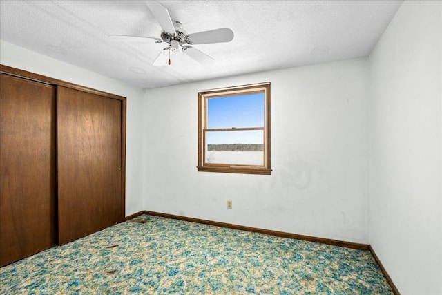 unfurnished bedroom with ceiling fan, carpet flooring, a closet, and a textured ceiling