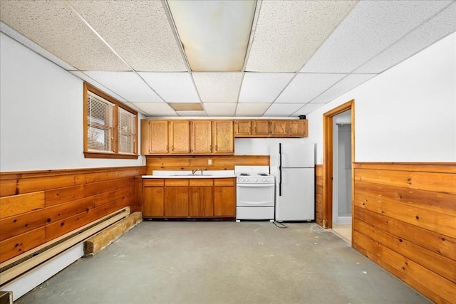 kitchen with wooden walls, sink, a baseboard heating unit, a drop ceiling, and white appliances