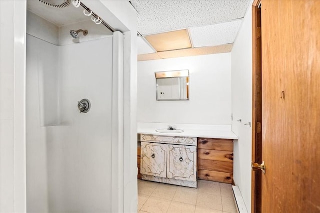 bathroom with vanity, a shower, and a drop ceiling