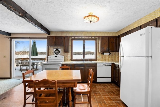 kitchen with white appliances, sink, dark brown cabinets, and a textured ceiling