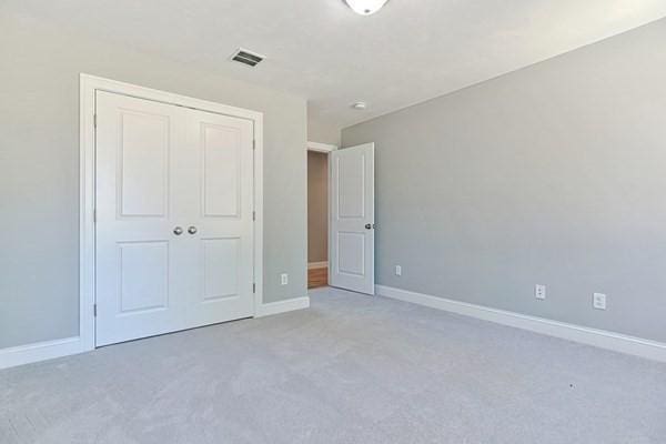 unfurnished bedroom featuring light colored carpet and a closet