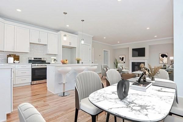 kitchen featuring decorative backsplash, a kitchen island, stainless steel stove, white cabinetry, and hanging light fixtures