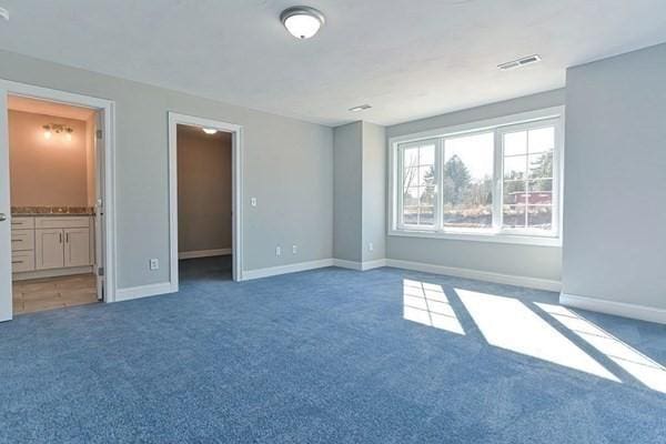 unfurnished bedroom featuring dark carpet and ensuite bath