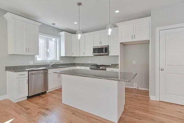 kitchen with white cabinetry, a kitchen island, stainless steel appliances, and decorative light fixtures