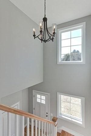 stairway with plenty of natural light, wood-type flooring, and a notable chandelier