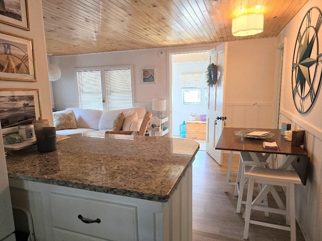 kitchen featuring wood ceiling, stone counters, hardwood / wood-style flooring, and white cabinets