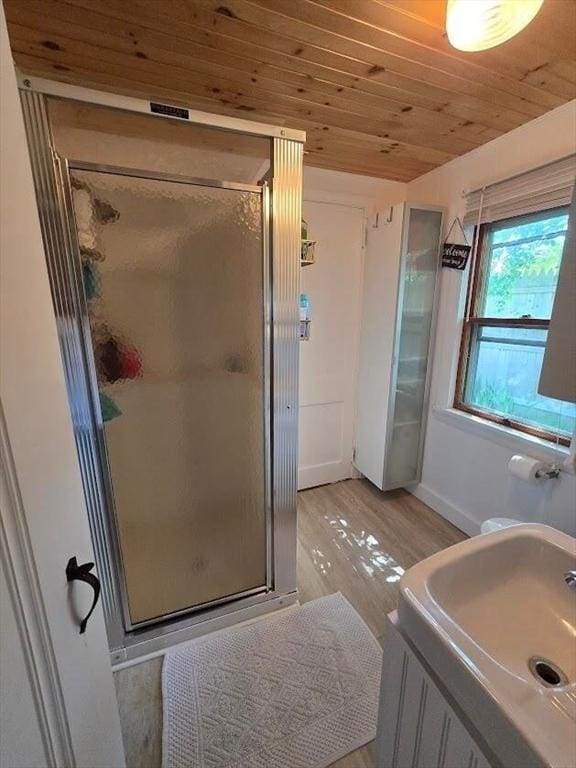 full bath featuring baseboards, wooden ceiling, a stall shower, and wood finished floors