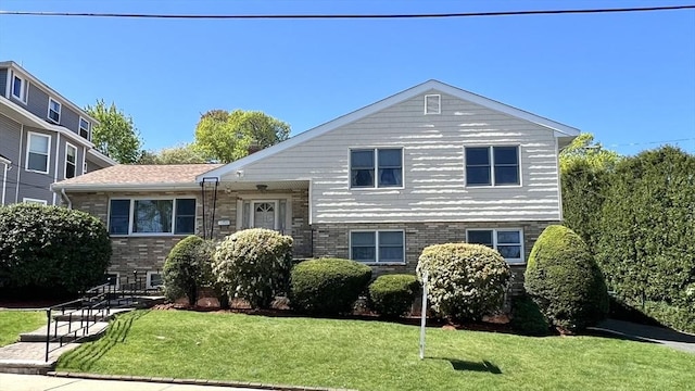 tri-level home with a front yard and brick siding