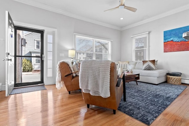 living area featuring a healthy amount of sunlight, light wood-style flooring, a ceiling fan, and ornamental molding