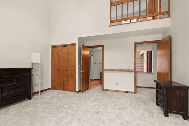 bedroom with light colored carpet, a high ceiling, and a closet