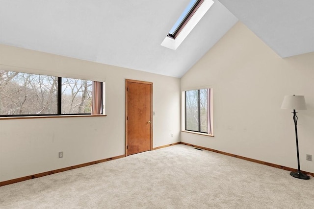 unfurnished room featuring a skylight, light carpet, and high vaulted ceiling