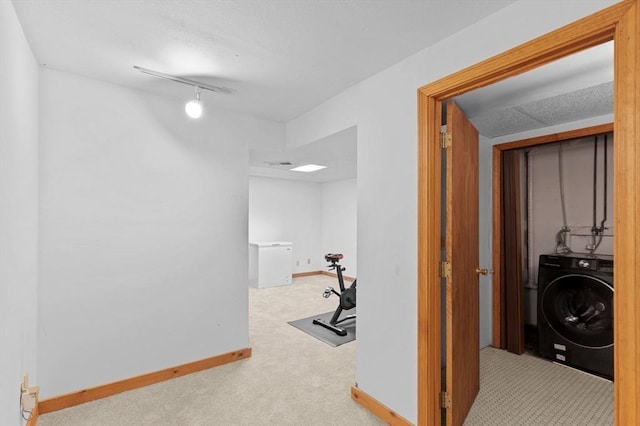 corridor featuring carpet floors, track lighting, and washer / dryer