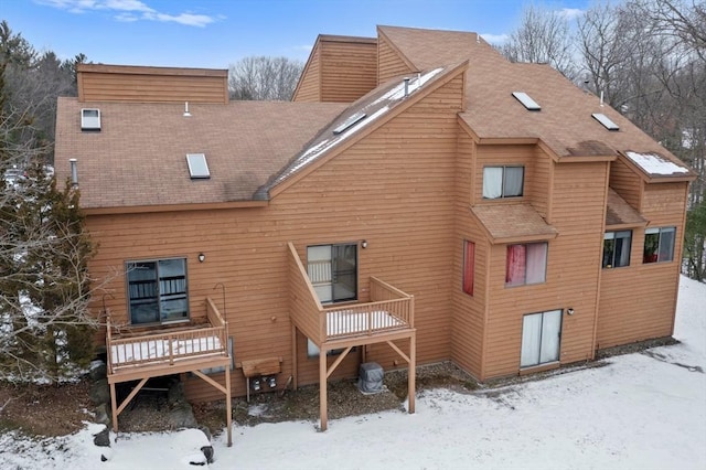 snow covered back of property featuring a deck