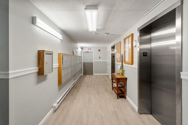 49 Melrose St Unit 4E, Melrose, MA 02176 - corridor with elevator, a baseboard heating unit, light wood-style floors, mail area, and baseboards