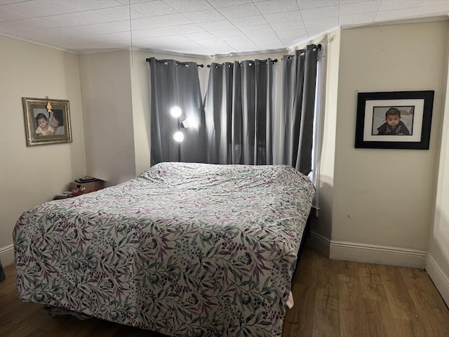 bedroom with baseboards, wood finished floors, and crown molding