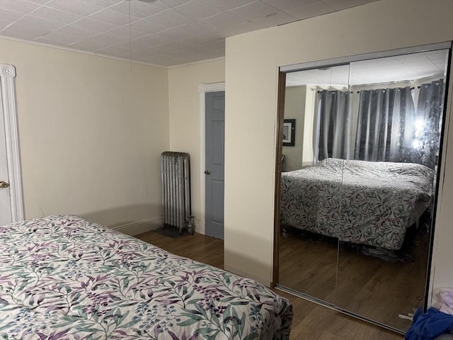 bedroom with radiator heating unit and wood finished floors