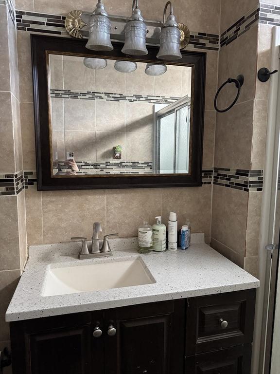 bathroom with tasteful backsplash, tile walls, and vanity