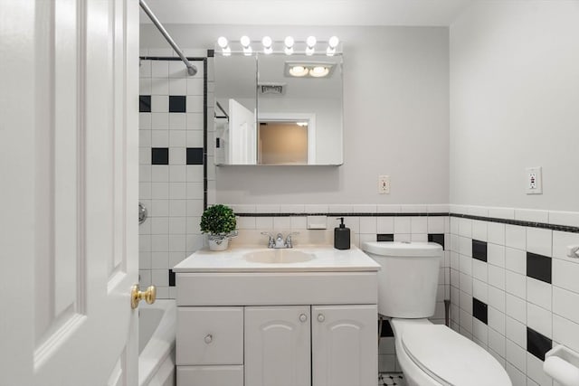 bathroom featuring vanity, toilet, and tile walls